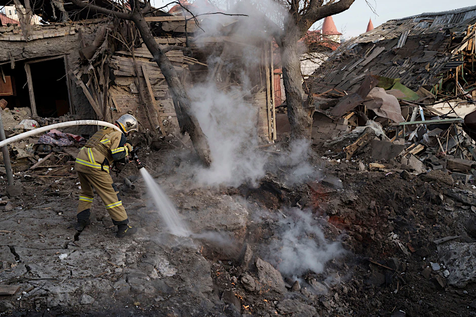 Feuerwehrleute löschen nach einem Beschuss auf die ukrainische Hauptstadt Kiew ein Feuer neben Häusern, die durch die Angriffe zerstört wurden.