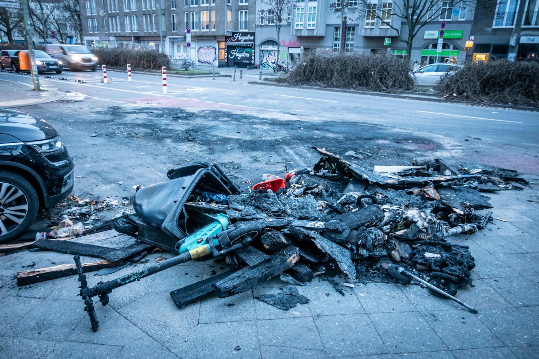 Überreste von verbrannten Mülltonnen und E-Scootern nach Randale in der Silvesternacht an der Sanderstraße Ecke Kottbusser Damm in Neukölln