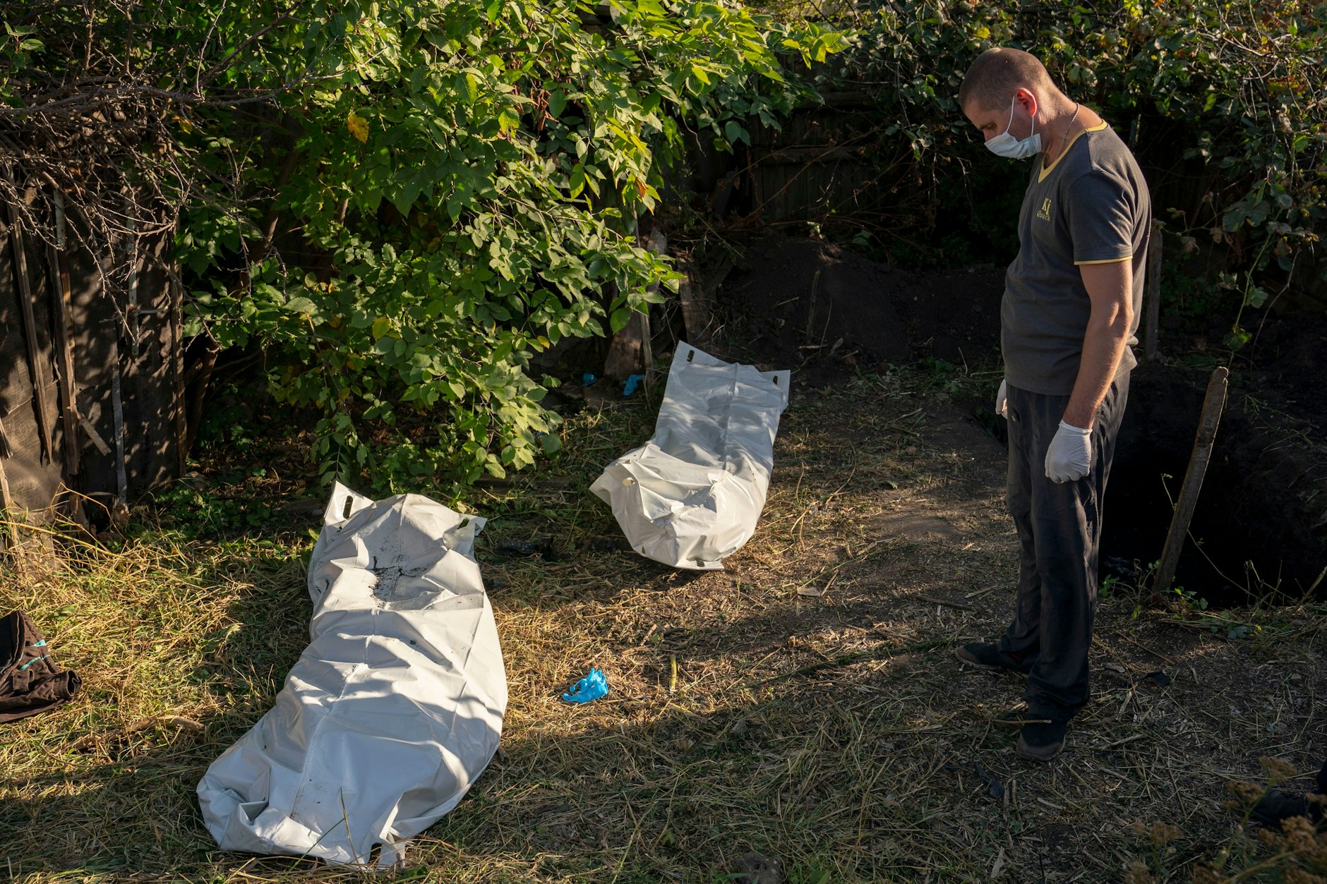Ein Ukrainer steht vor zwei Säcken mit Leichen im Dorf Hrakowe in der Region Charkiw. 