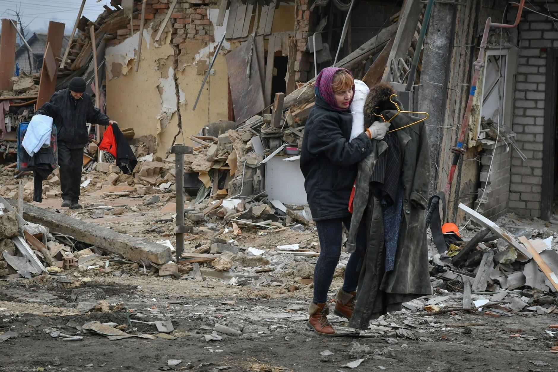 Anwohner tragen ihre Habseligkeiten aus von Bomben zerstörten Häusern.