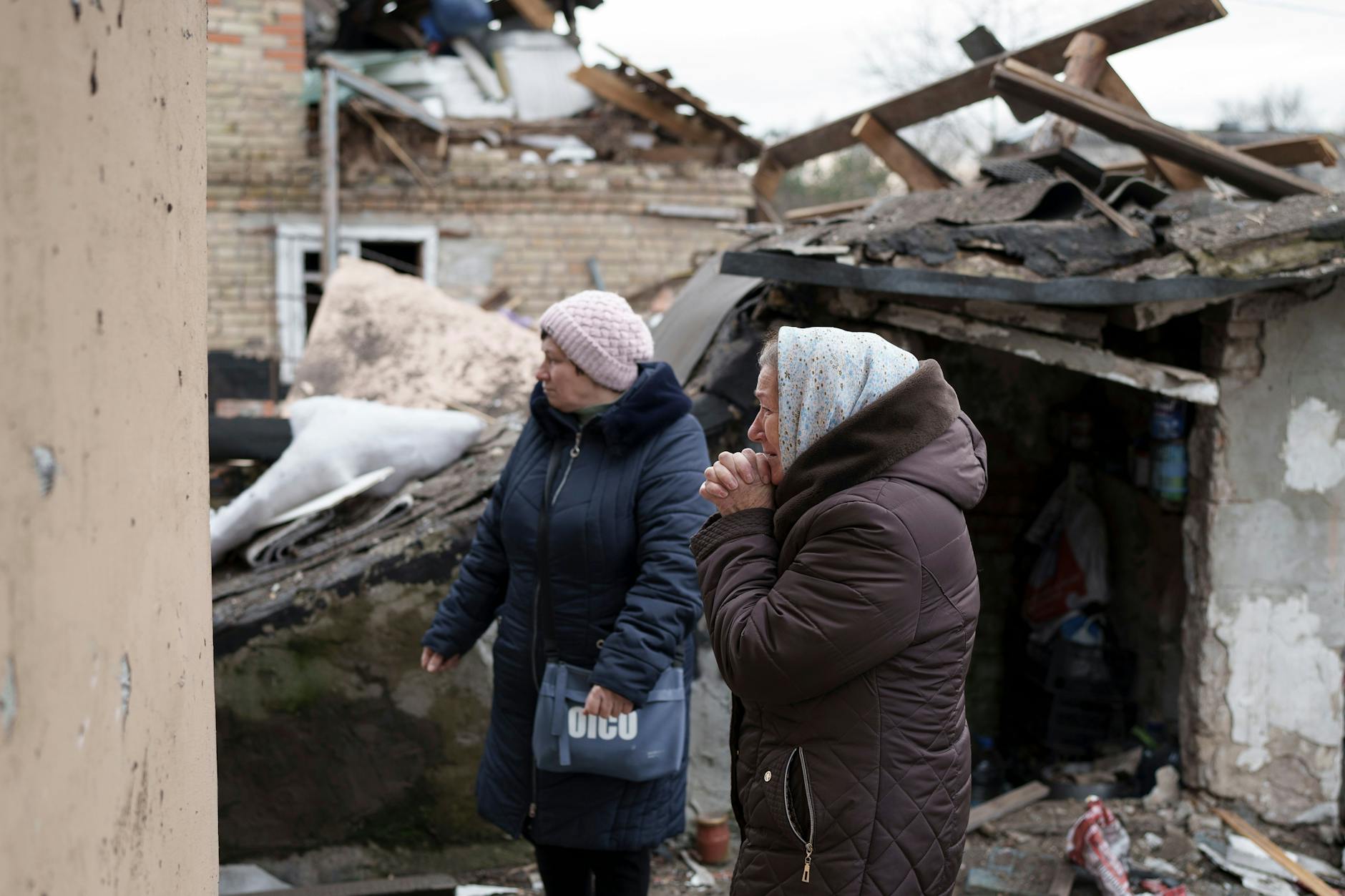 Zwei Frauen in den Trümmern eines durch eine Drohne zerstörten Hauses in Kiew, eine hat die Hände verzweifelt vor dem Gesicht gefaltet.