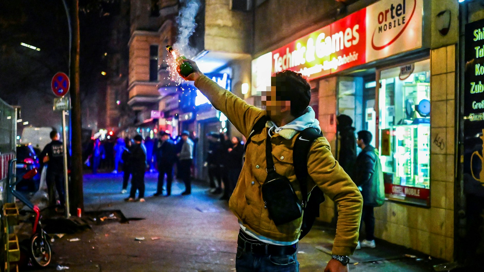 Ein Mann in Neukölln schießt eine Silvesterrakete aus der Hand ab.