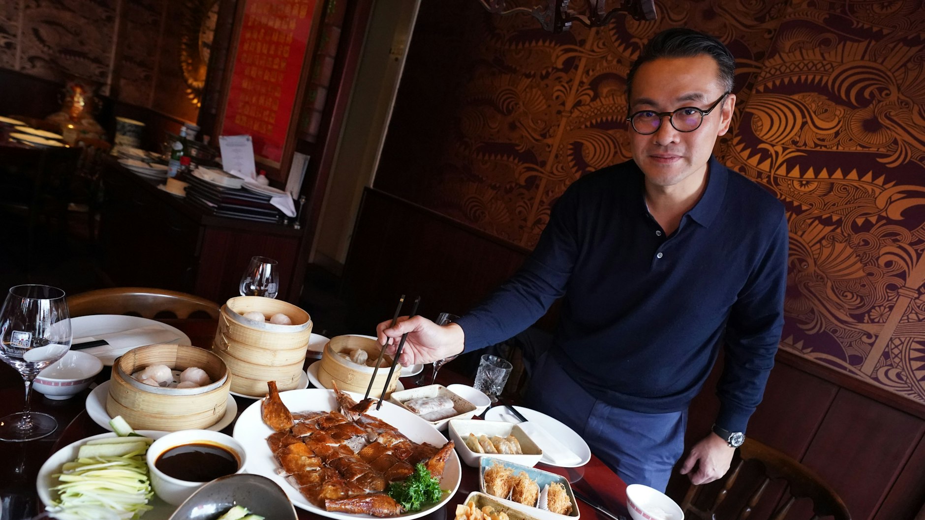 Restaurant-Betreiber Dennis Kwong serviert eine Pekingente und weitere Spezialitäten auf einem Tisch im chinesischen Restaurant "Dim sum Haus" in Hamburg.