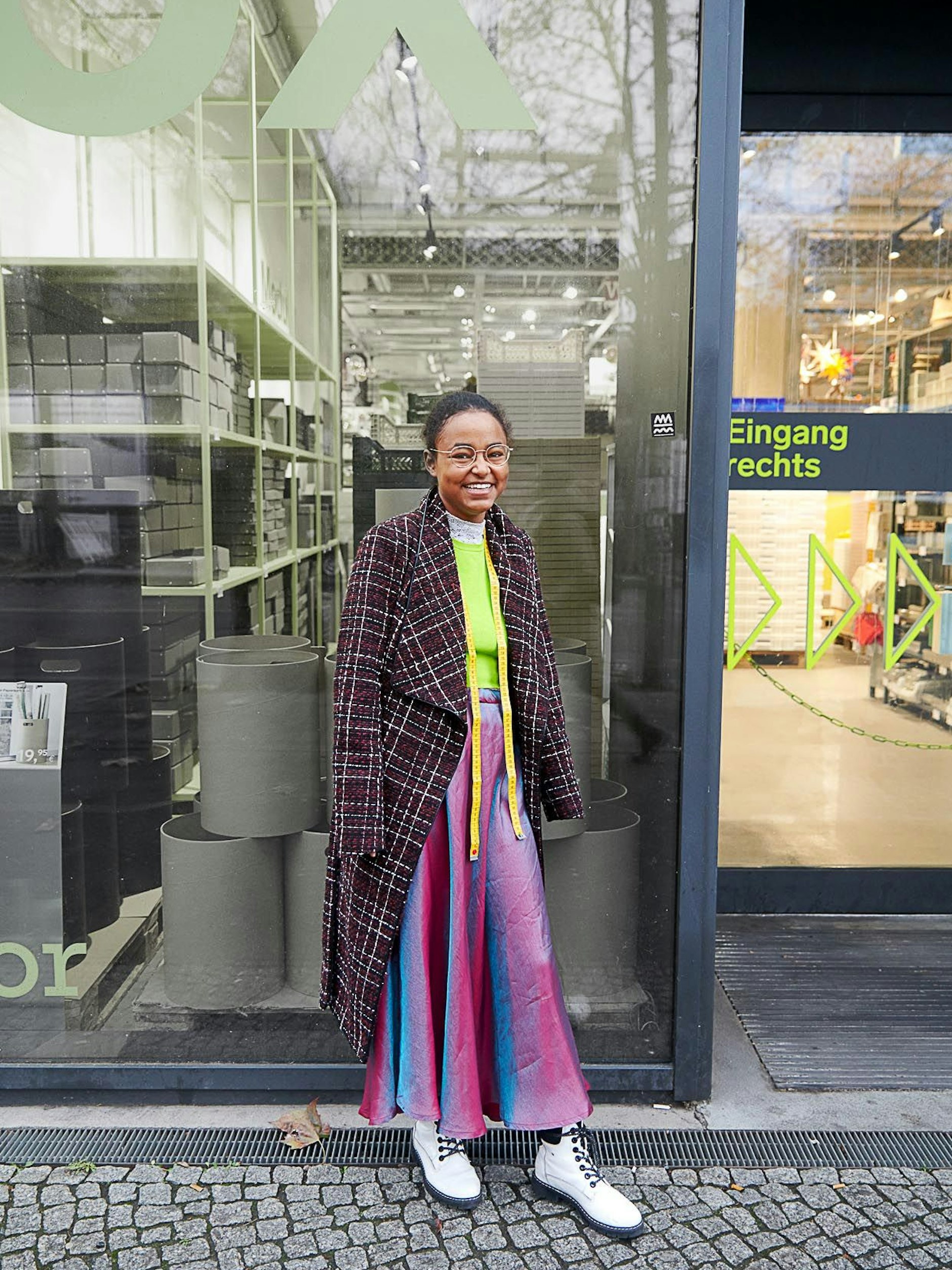 Bezüglich Ayenachews Job müssen wir nicht lange grübeln. Wir sehen sie an ihrem Arbeitsplatz in der Schneiderei „à la mode“ im Aufbau Haus hantieren, wo sie ein Praktikum macht. Ihren Look hat sich die Lichtenbergerin bis auf Mantel und Schuhe selbst zusammengeschneidert.