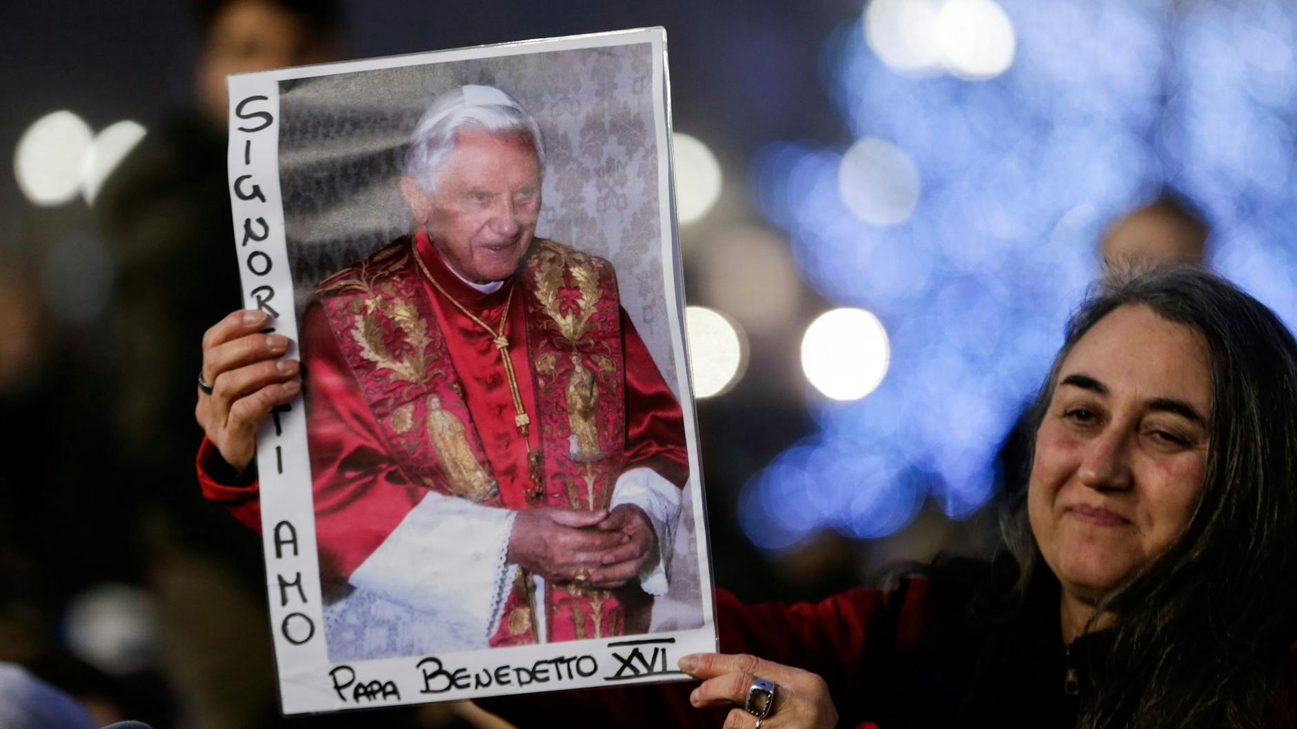 Eine Frau hält ein Bild des verstorbenen emeritierten Papstes Benedikt XVI. in Händen.