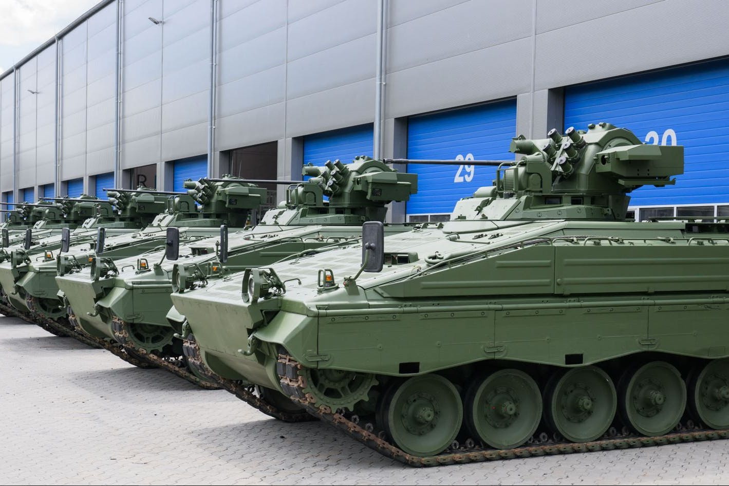 Wieder aufbereitete Marder-Schützenpanzer stehen vor einer Halle.