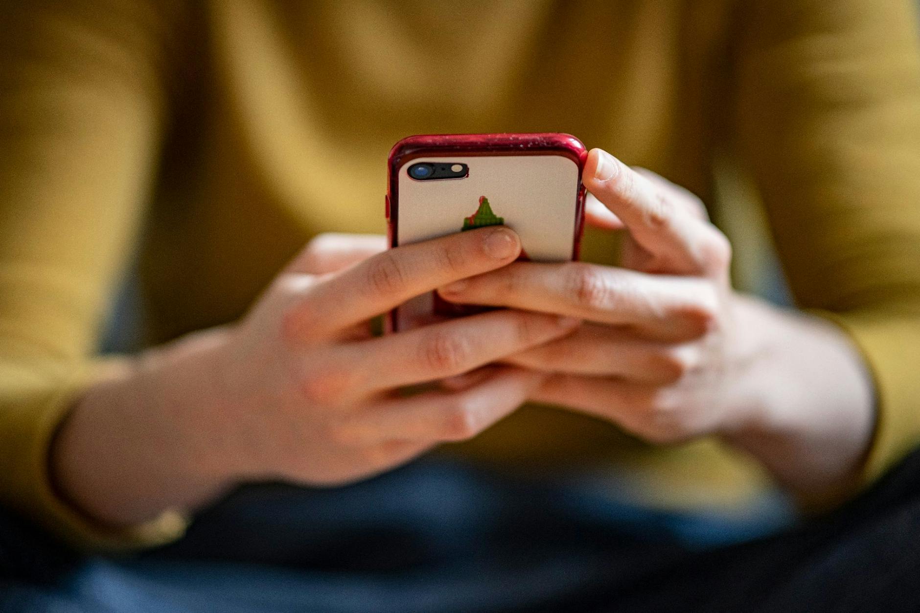 ARCHIV - Eine junge Frau hält ein Smartphone in der Hand.