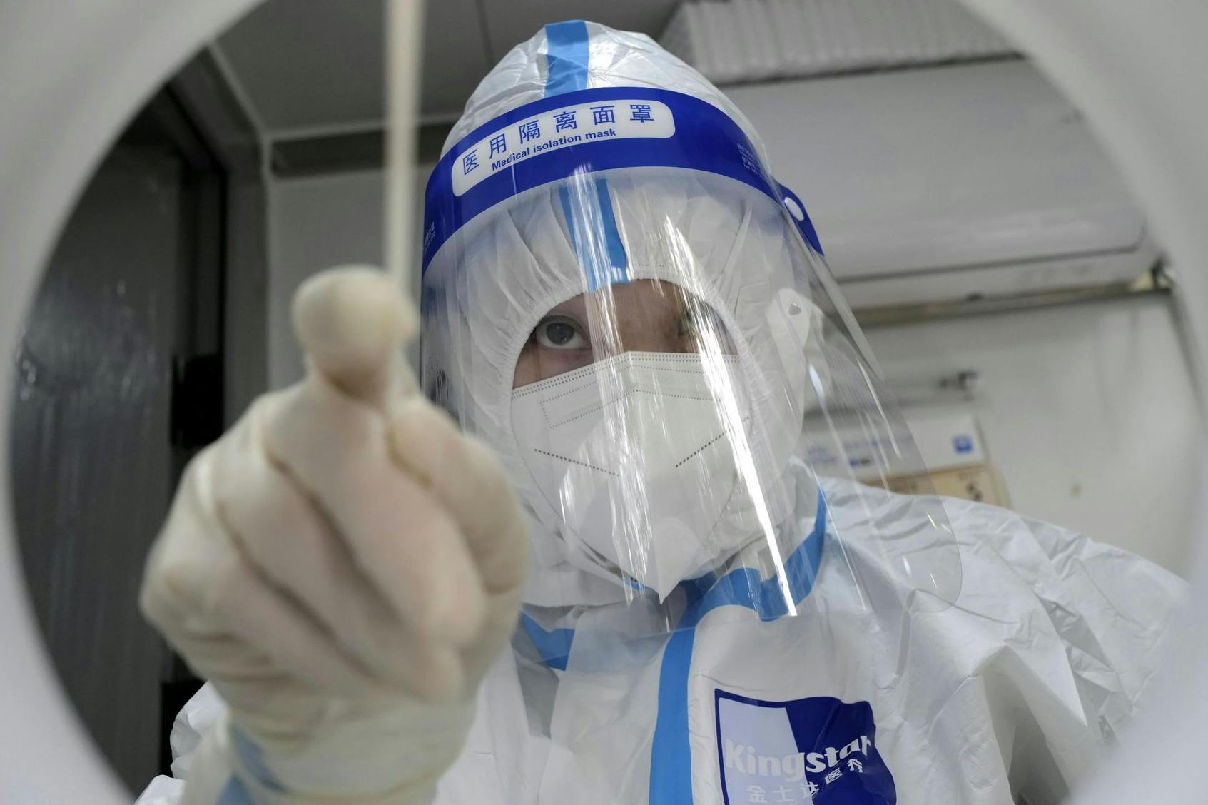 Ein medizinischer Mitarbeiter in Schutzkleidung führt einen PCR-Test durch.