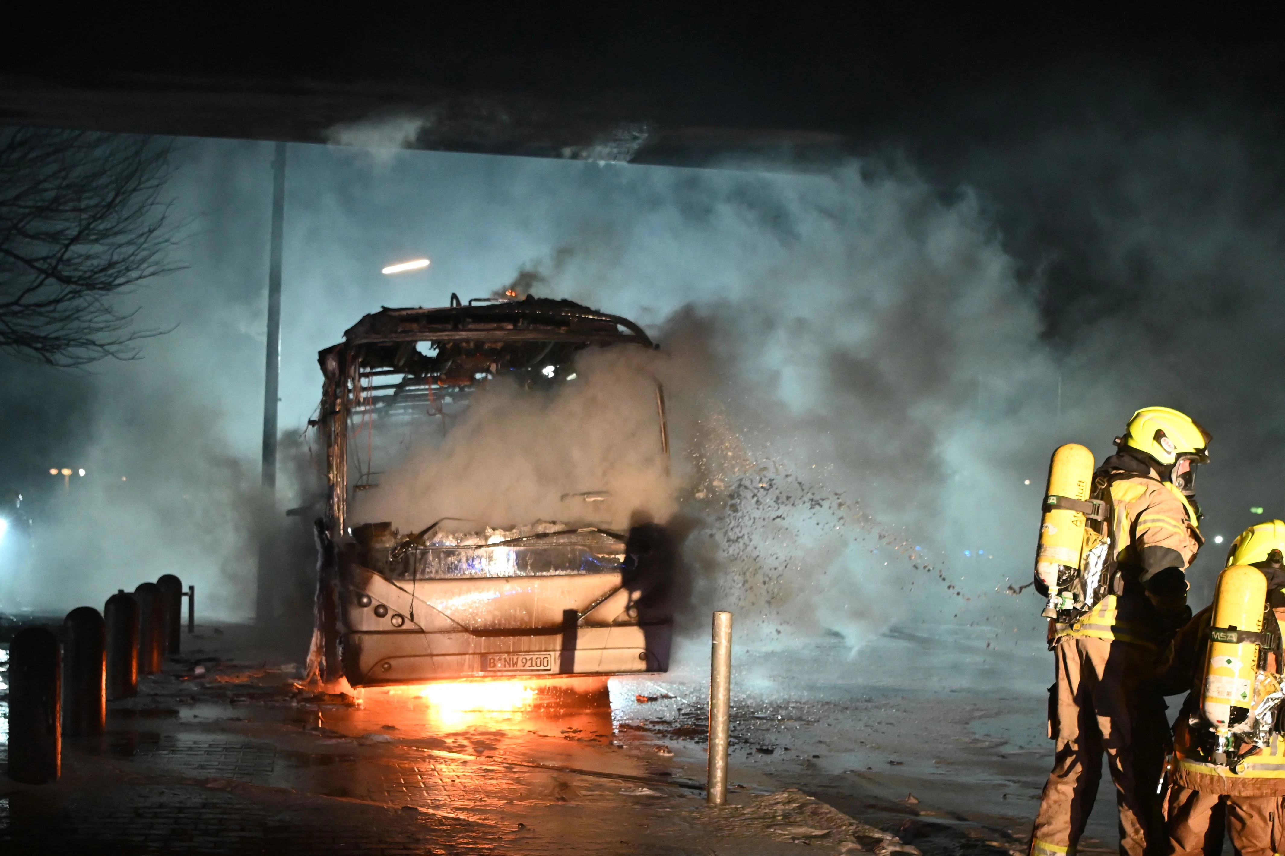 Silvesternacht in Neukölln: Feuerwehrmänner löschen an der Sonnenallee einen Reisebus, der von Unbekannten angezündet worden war.