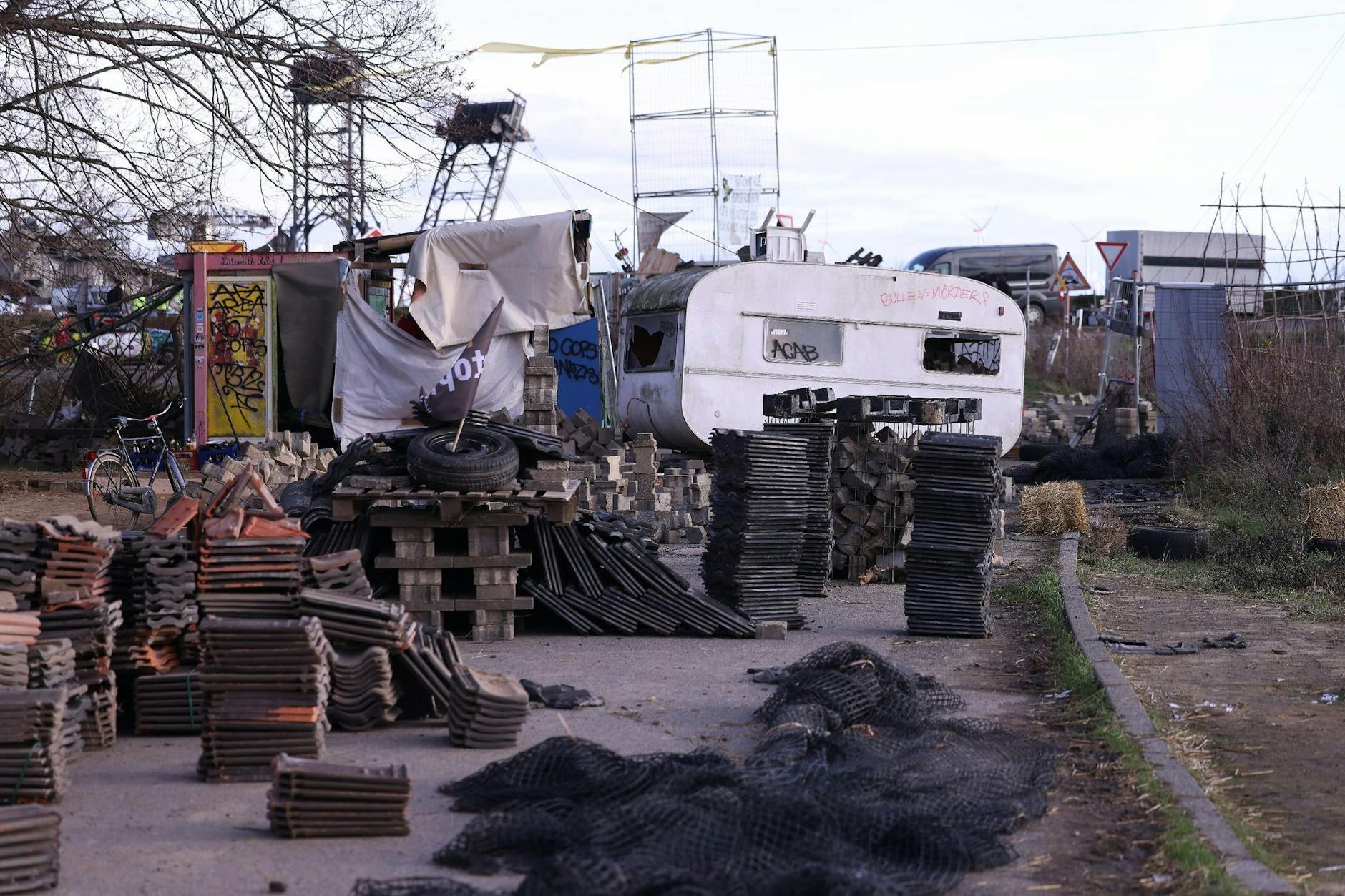 Klimaschutzaktivisten haben eine Straße im Braunkohledorf Lützerath mit einem Wohnwagen und Steinen verbarrikadiert.