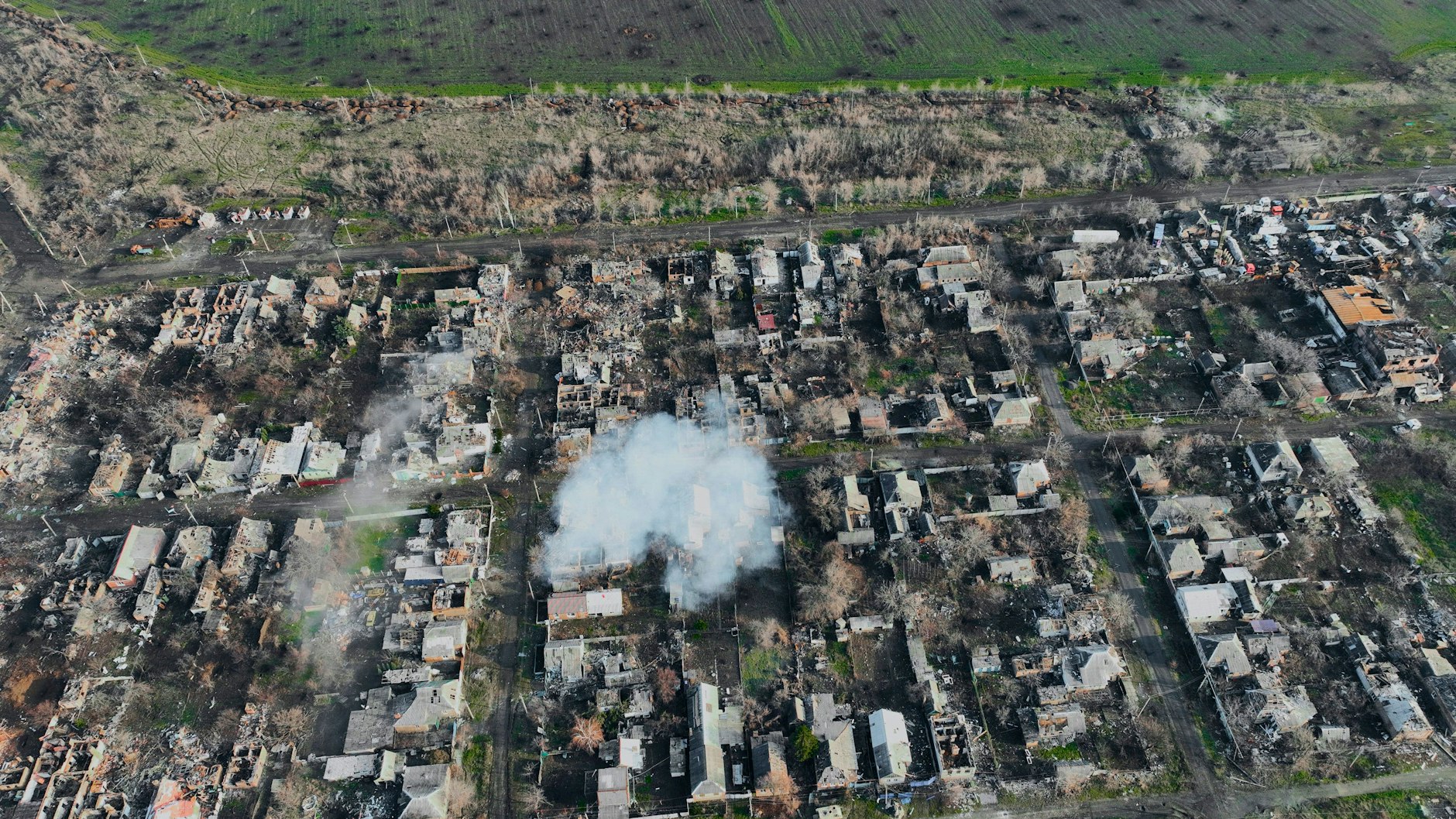 Am Rande der Stadt Bachmut ist kaum ein Haus noch intakt, das Feld daneben ist voller Granattrichter.
