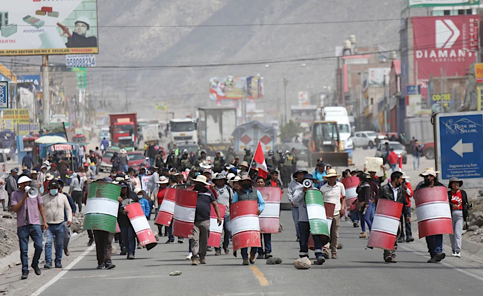 Demonstranten marschieren bei einem Protest gegen die Regierung von Präsidentin Boluarte mit behelfsmäßigen Schildern über eine Straße im peruanischen Arequipa.  