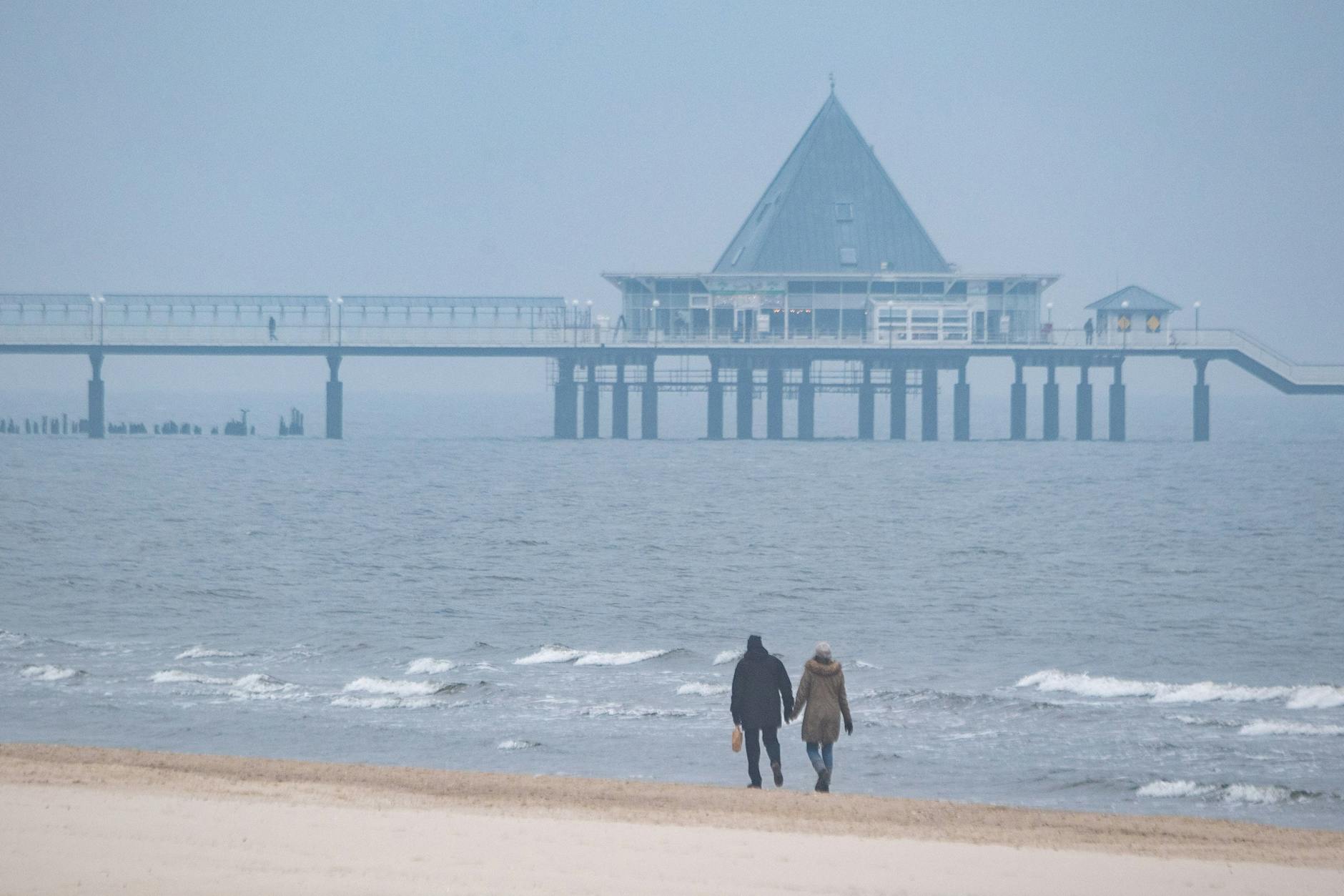 Ahlbeck: Spaziergänger sind am Strand der Insel Usedom unterwegs. In Zukunft soll der Urlaubsort mit dem Zug schneller von Berlin aus erreichbar sein.