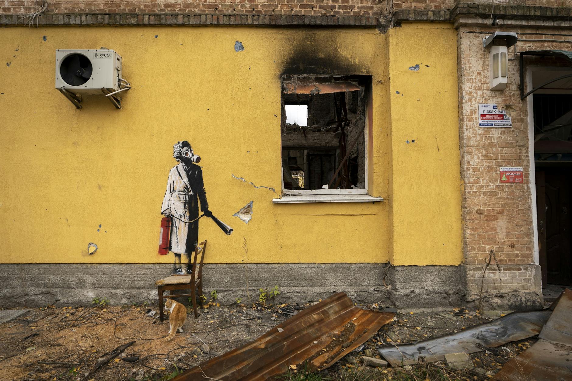 Ukraine: Das undatierte Handout-Foto von Banksy zeigt ein kriegszerstörtes Haus. Auf der gelben Wand des Gebäudes ist eine Person zu sehen, die eine Gasmaske und einen Feuerlöscher trägt. 