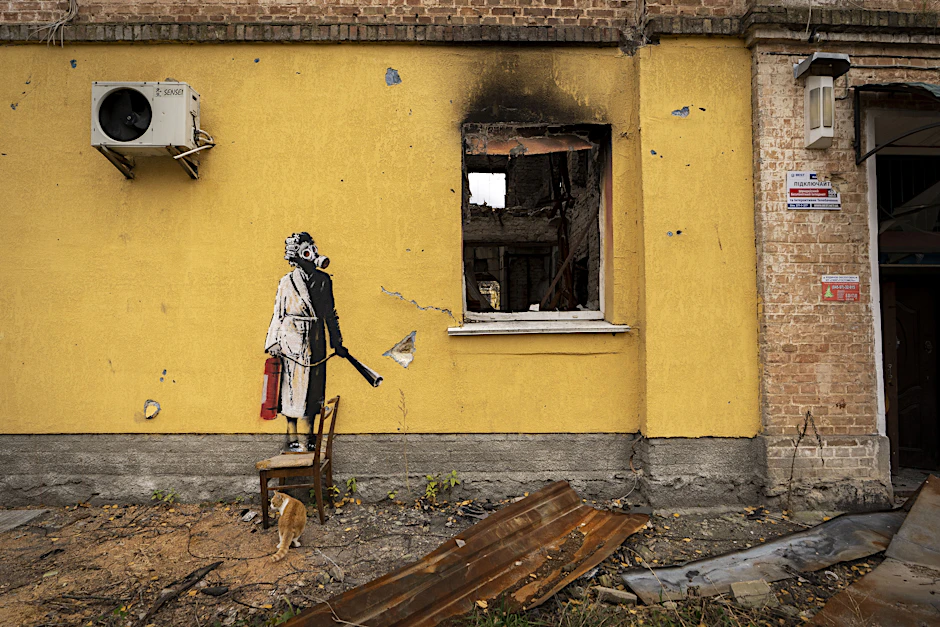 Ukraine: Das undatierte Handout-Foto von Banksy zeigt ein kriegszerstörtes Haus. Auf der gelben Wand des Gebäudes ist eine Person zu sehen, die eine Gasmaske und einen Feuerlöscher trägt.&nbsp;