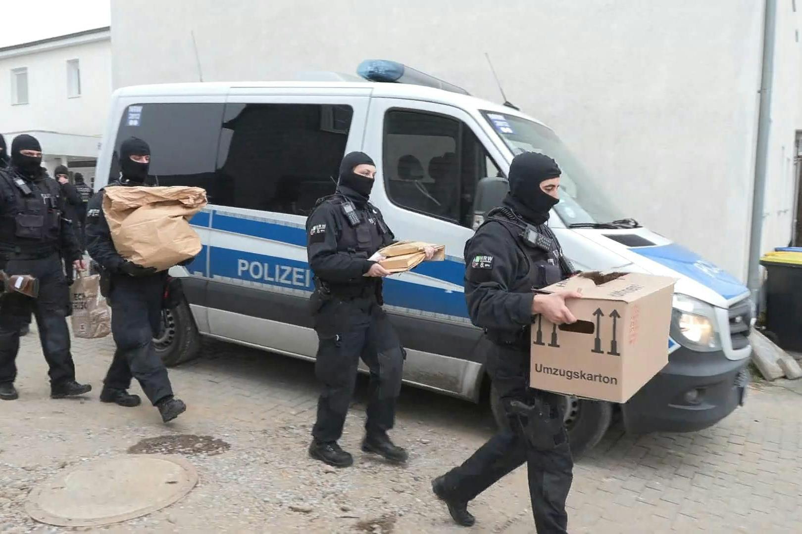 Polizisten tragen bei einer Razzia Beweismittel aus einem Haus. (Symbolbild)