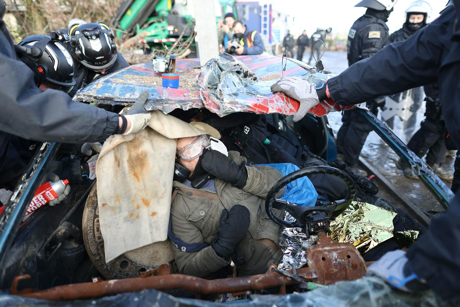 Die Polizei schneidet einen Klimaaktivisten aus einem Auto, das als Straßensperre im besetzten Braunkohleort Lützerath genutzt wird. Der Energiekonzern RWE will die unter Lützerath liegende Kohle abbaggern - dafür soll der Weiler auf dem Gebiet der Stadt Erkelenz am Braunkohletagebau Garzweiler II abgerissen werden. Die Polizei hat mit der Räumung des Geländes begonnen. 