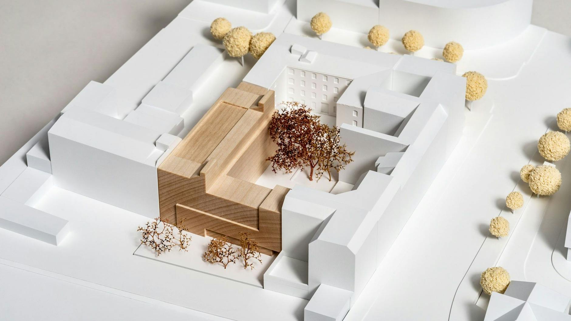 Der dunkle Teil des Modells zeigt den Neubau. Der vordere Riegel schirmt den Hof zum lauten Stadtring hin ab.