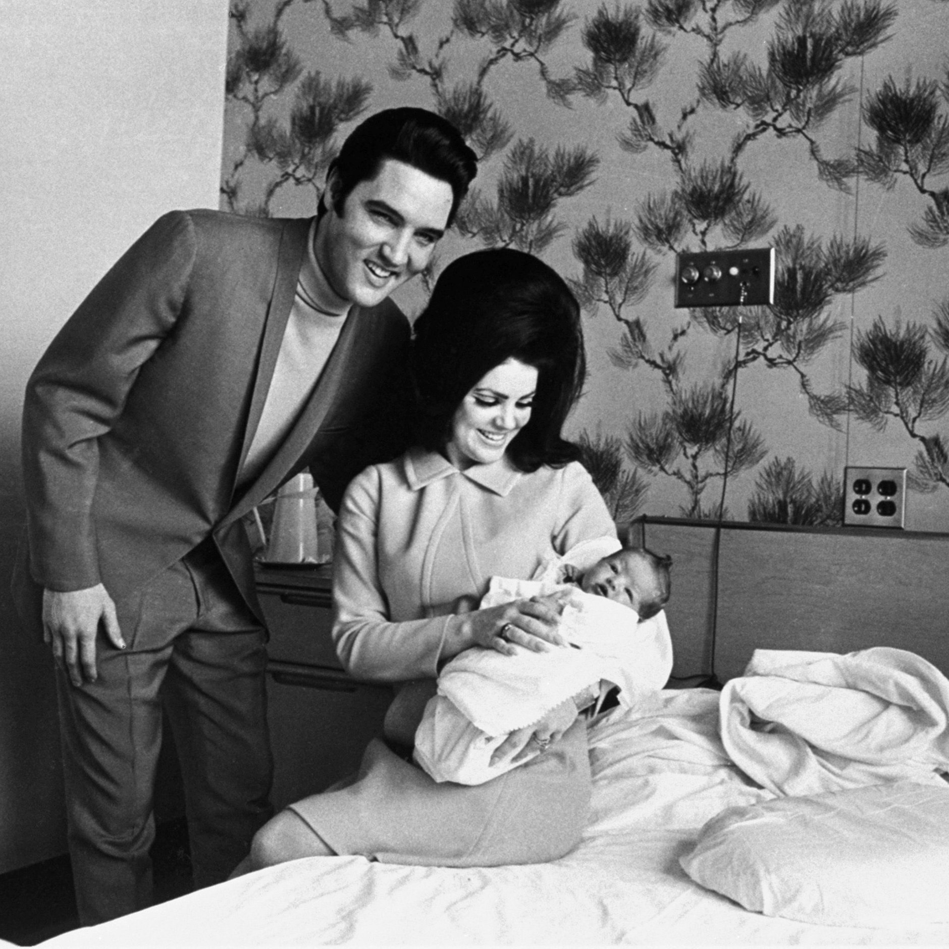 Lisa Marie Presley liegt auf dem Schoß ihrer Mutter Priscilla neben ihrem Vater Elvis Presley.