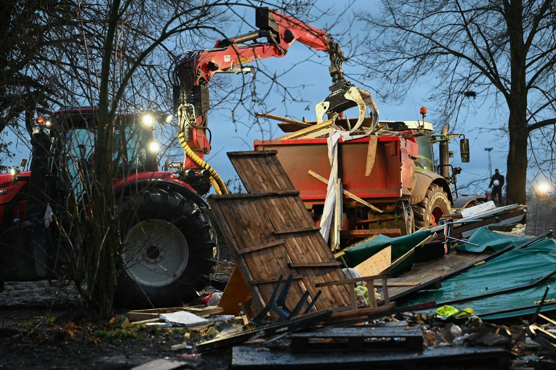 Ein Bagger lädt in Lützerath Reste von Hütten auf einen Lkw.