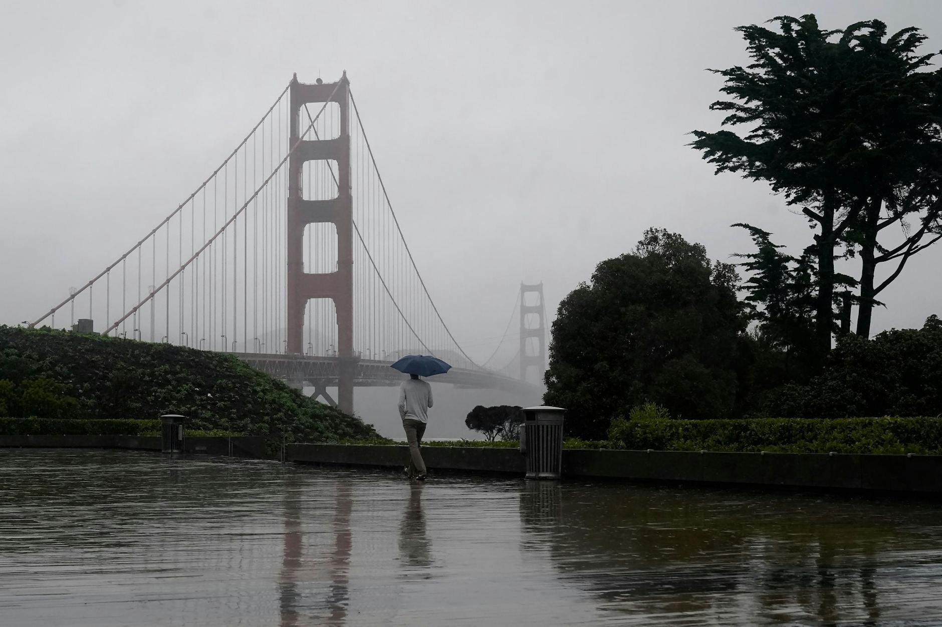 Ein Mann geht bei Regen an der Golden Gate Bridge vorbei, dem Wahrzeichen von San Francisco.