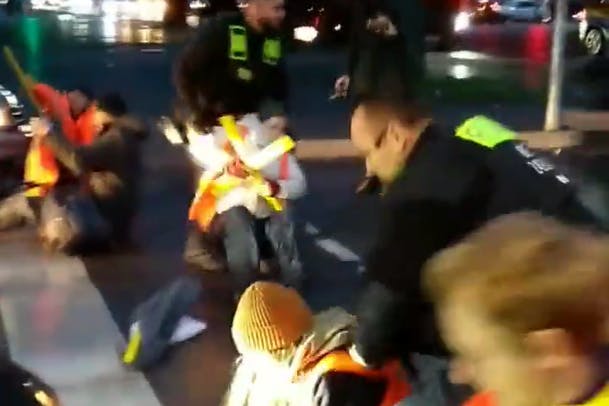 Polizisten zerren die Klima-Kleber von der Straße.