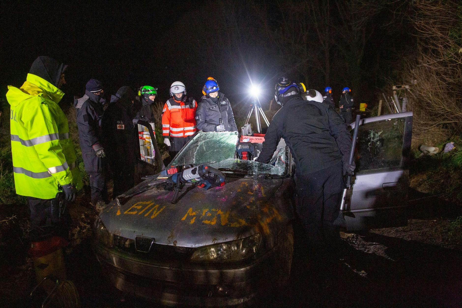 In dem Autowrack hat sich eine Aktivistin durch das Bodenblech in den darunterliegenden Weg mit den Füßen einzementiert.