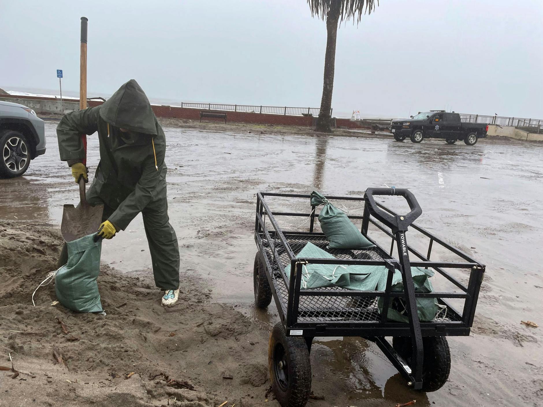 In Aptos schaufelt eine Frau im strömenden Regen Sand in Säcke.