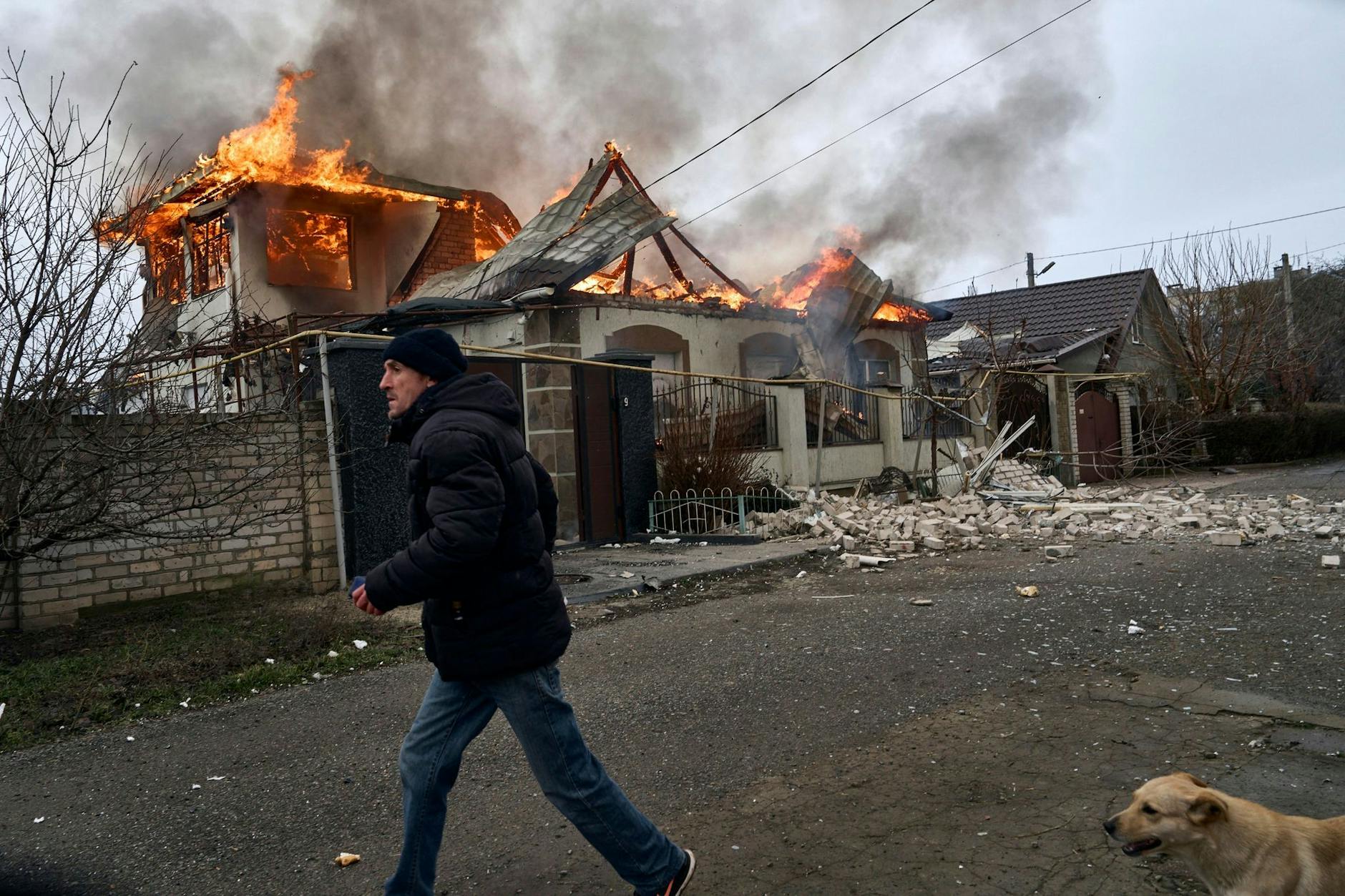 Ein Anwohner läuft an einem brennenden Haus in Cherson vorbei, das nach ukrainischen Angaben bei russischem Beschuss getroffen wurde.