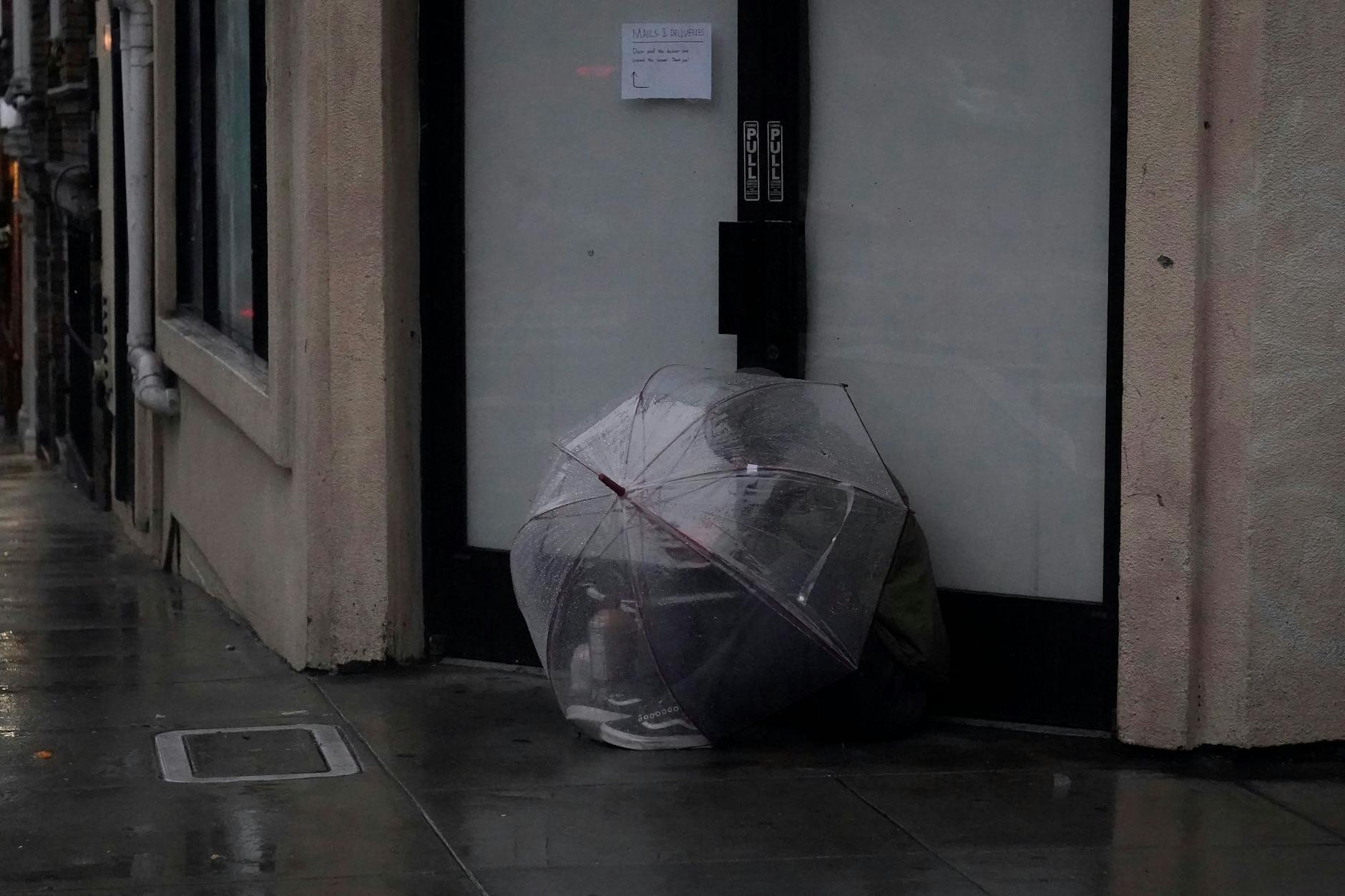 Eine Person versucht in San Francisco, sich unter einem Schirm vor Regen zu schützen.