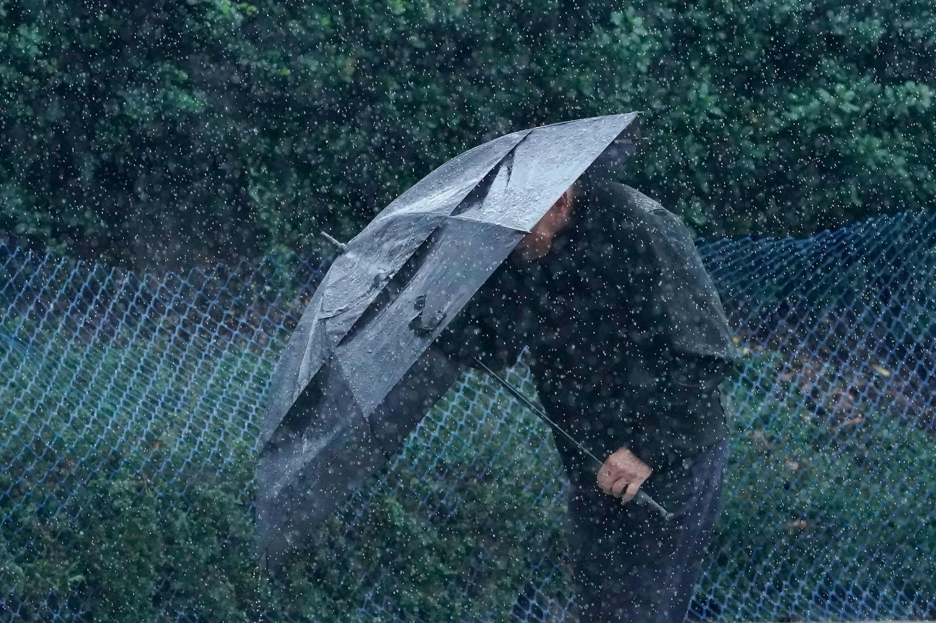 dpatopbilder - Ein Mann schützt sich in San Francisco vor Wind und Regen.