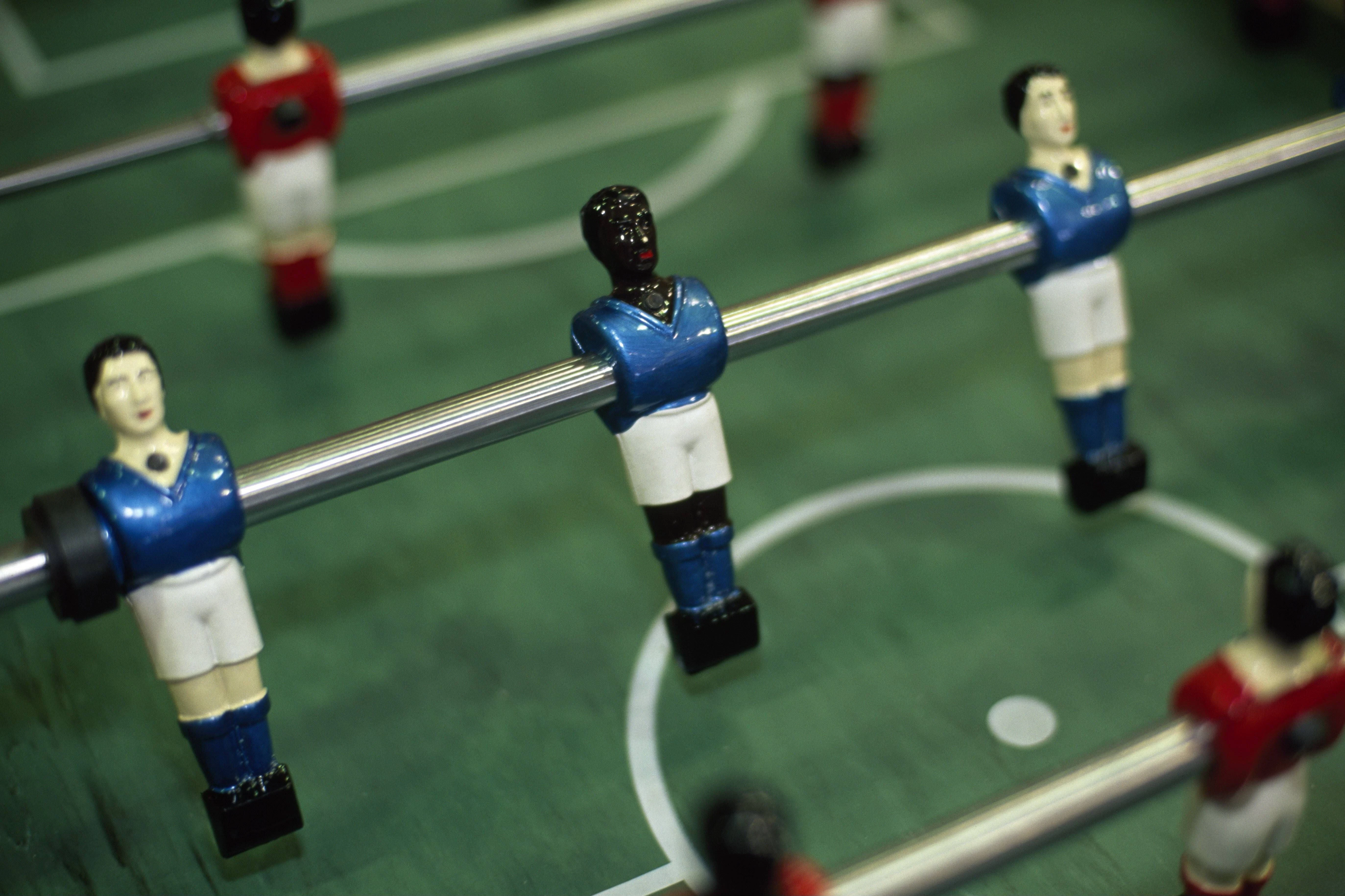 Ein Kickertisch mit weißen und schwarzen Spielfiguren.