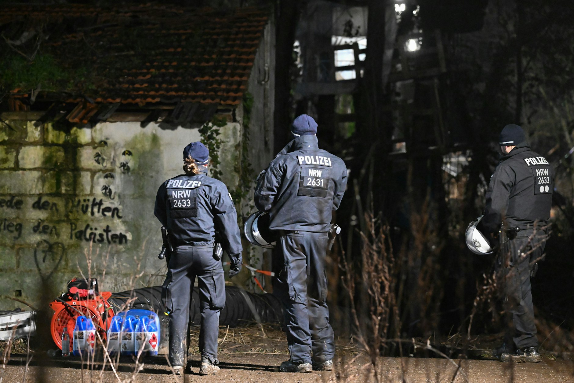 Polizeikräfte stehen in Lützerath vor dem Gebäude, in dem sich der Eingang zu dem Tunnel befindet. Die Lüftungsanlage sorgt dafür dass den zwei Klimaaktivisten nicht der Sauerstoff ausgeht.