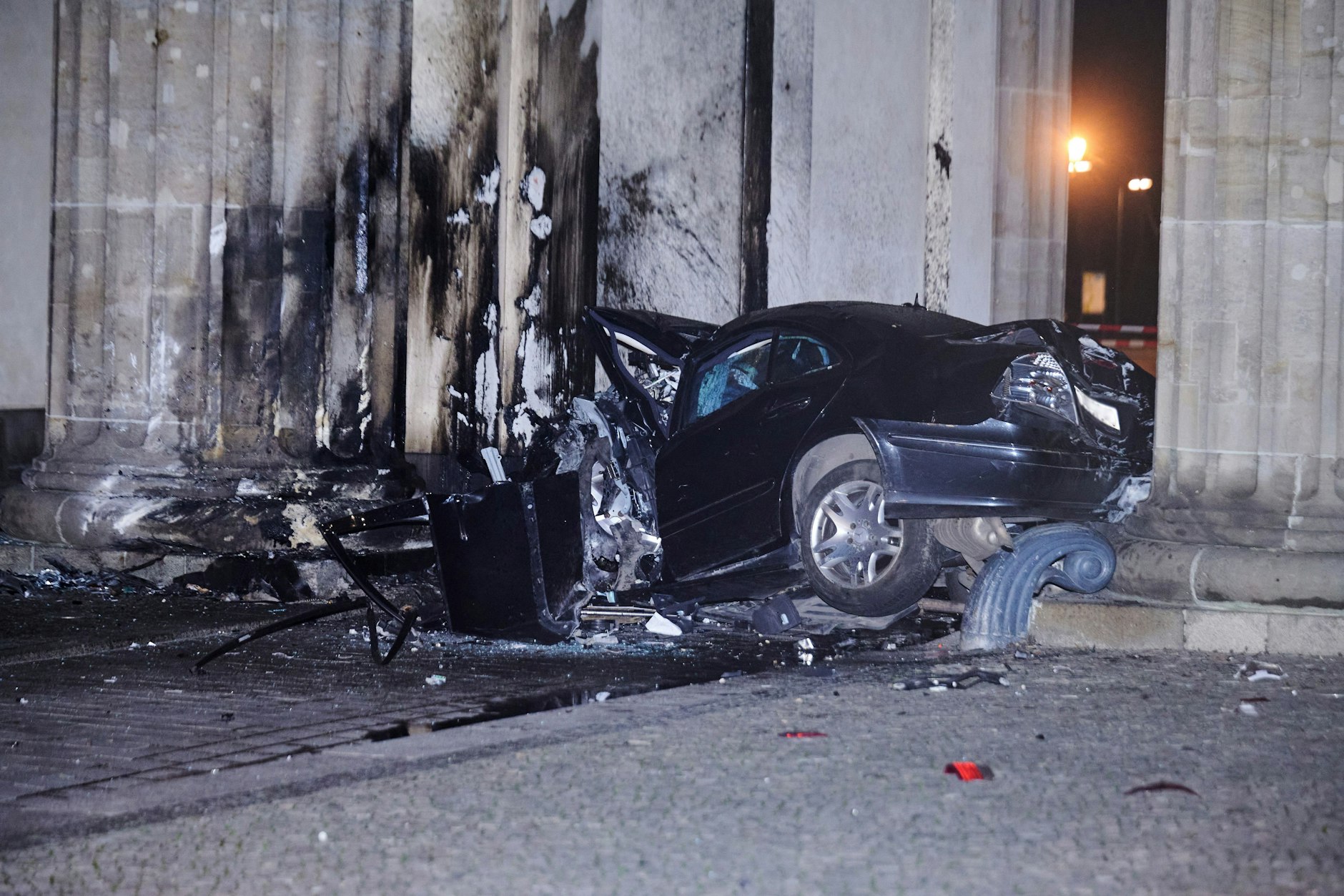 Das völlig zerstörte Auto hängt zwischen zwei Säulen des Brandenburger Tors.
