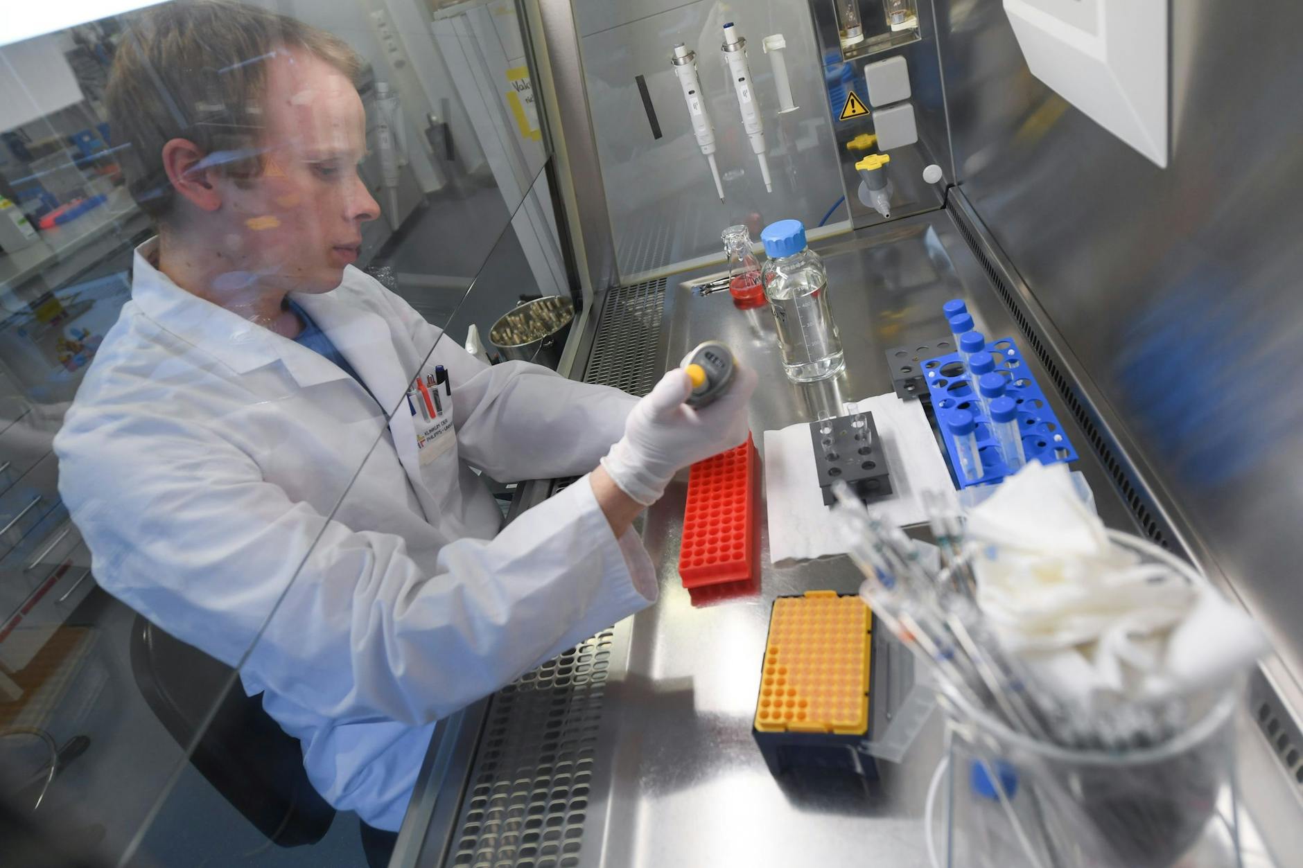 Doktorand Lennart Kaemper arbeitet in einem Forschungslabor des Instituts für Virologie der Philipps-Universität Marburg an einer Sterilwerkbank. 