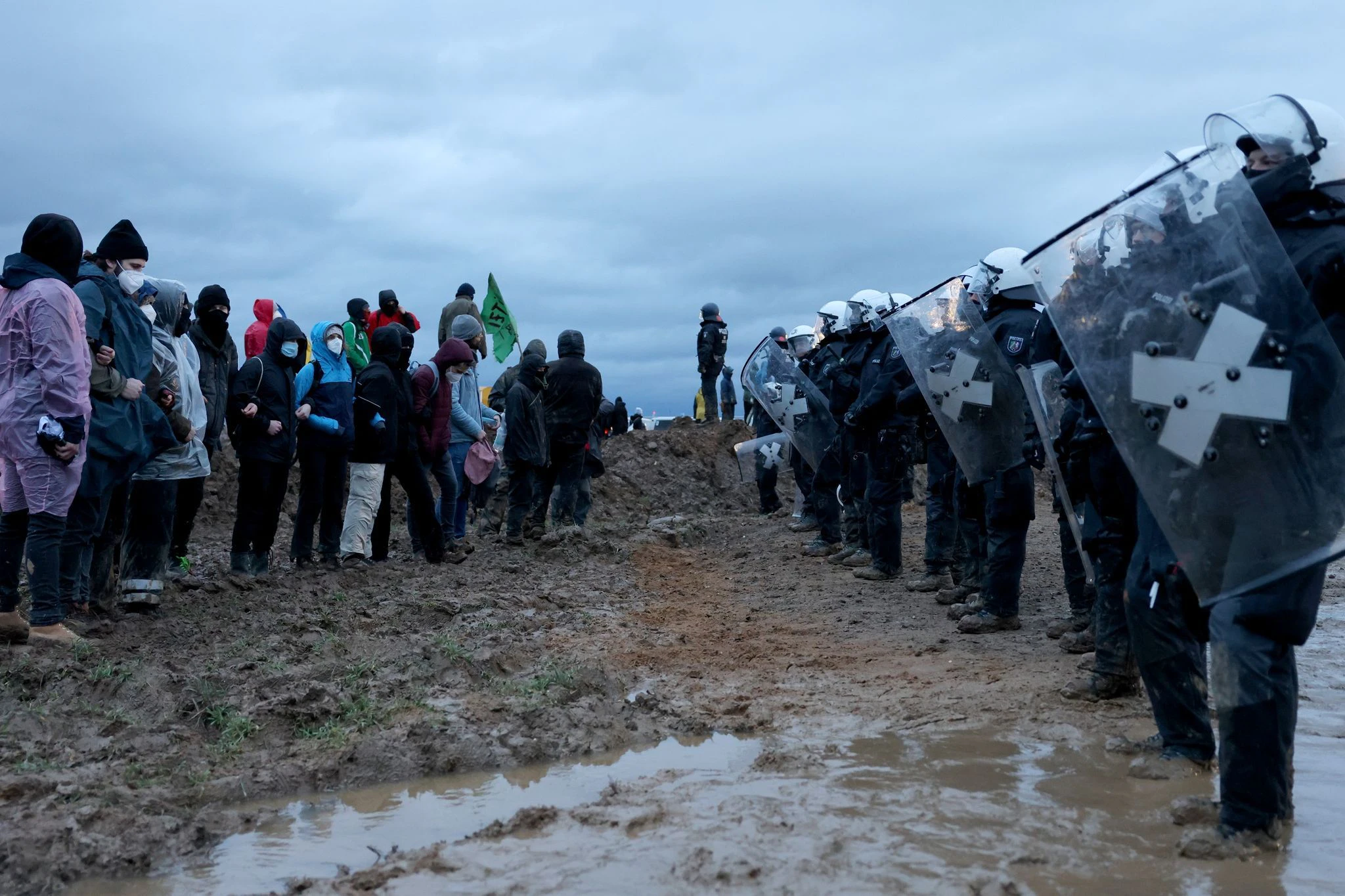 Polizisten und Demonstranten stehen sich am Rande des Braunkohletagebaus gegenüber.  