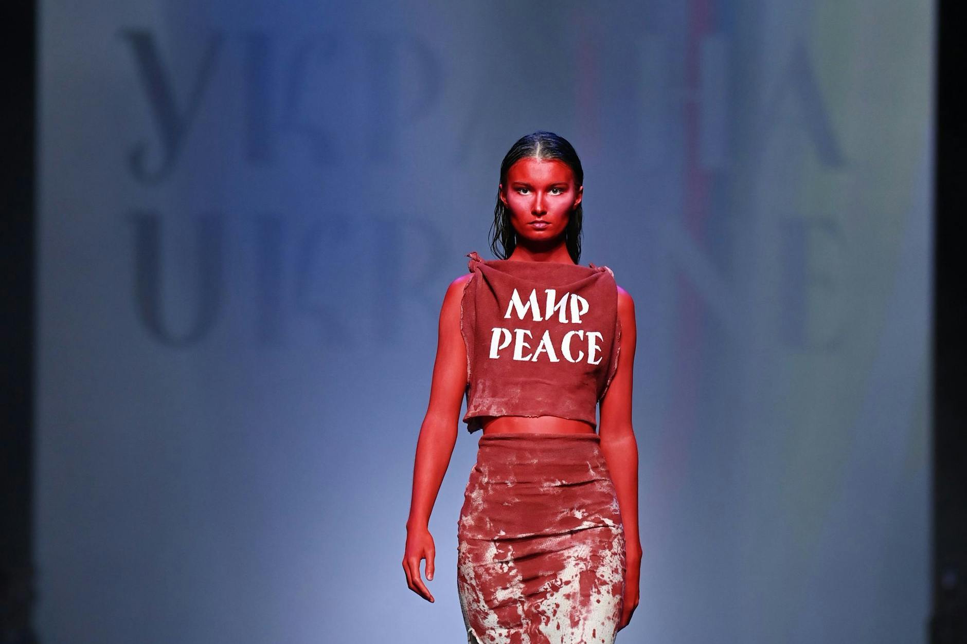 März 2022: Im Kraftwerk Berlin trägt ein Model bei der Show des ukrainischen Designers Jean Gritsfeldt ein blutig-rotes Outfit mit der Aufschrift „Peace“.