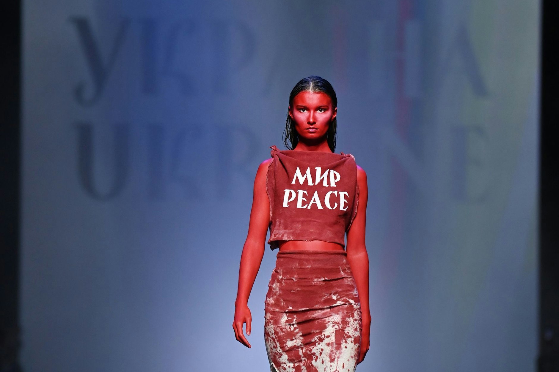 März 2022: Im Kraftwerk Berlin trägt ein Model bei der Show des ukrainischen Designers Jean Gritsfeldt ein blutig-rotes Outfit mit der Aufschrift „Peace“.