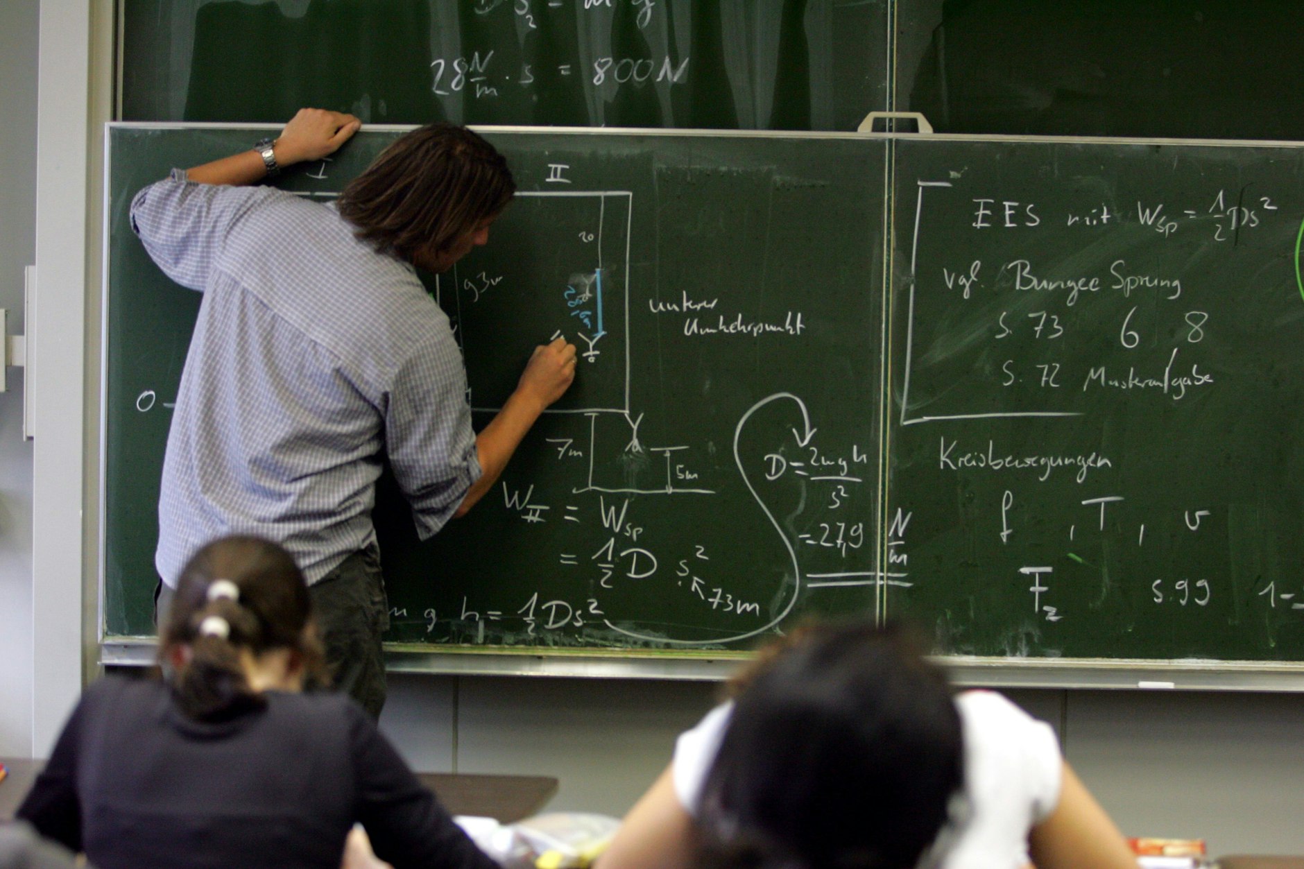 Ein Lehrer schreibt im Physik-Unterricht Formeln an die Tafel. In Berlin arbeiten Quereinsteiger ohne Rechtssicherung.