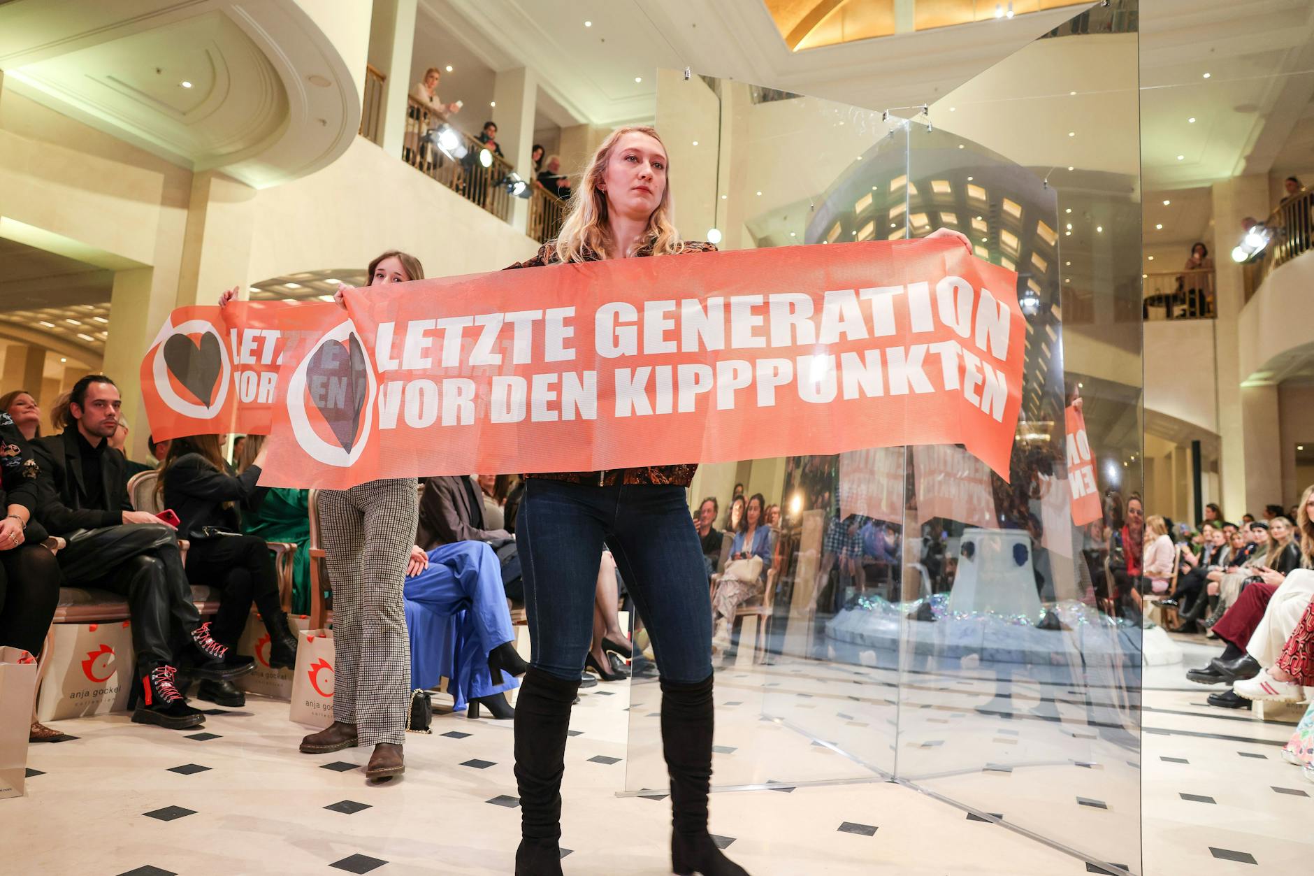 Protest bei der Fashion Show der Designerin Anja Gockel im Adlon Kempinski: Demonstrantinnen der Letzten Generation halten Transparente hoch. 