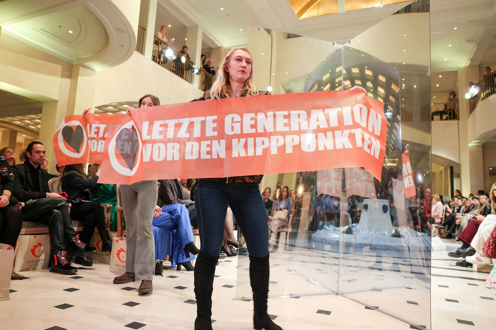 Protest bei der Fashion Show der Designerin Anja Gockel im Adlon Kempinski: Demonstrantinnen der Letzten Generation halten Transparente hoch.&nbsp;