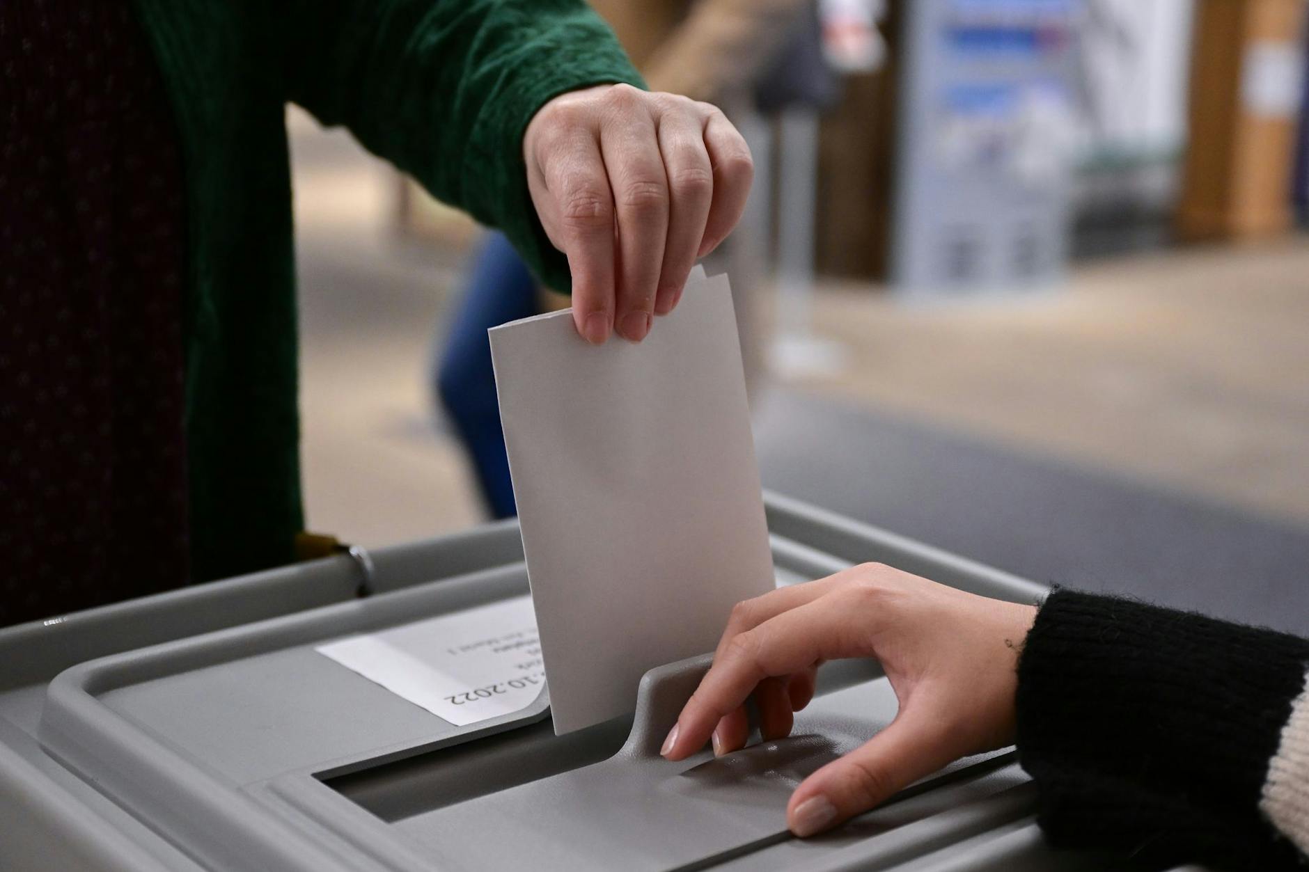 Ein Wähler steckt bei einer Wahl seinen Wahlzettel in eine Urne. 