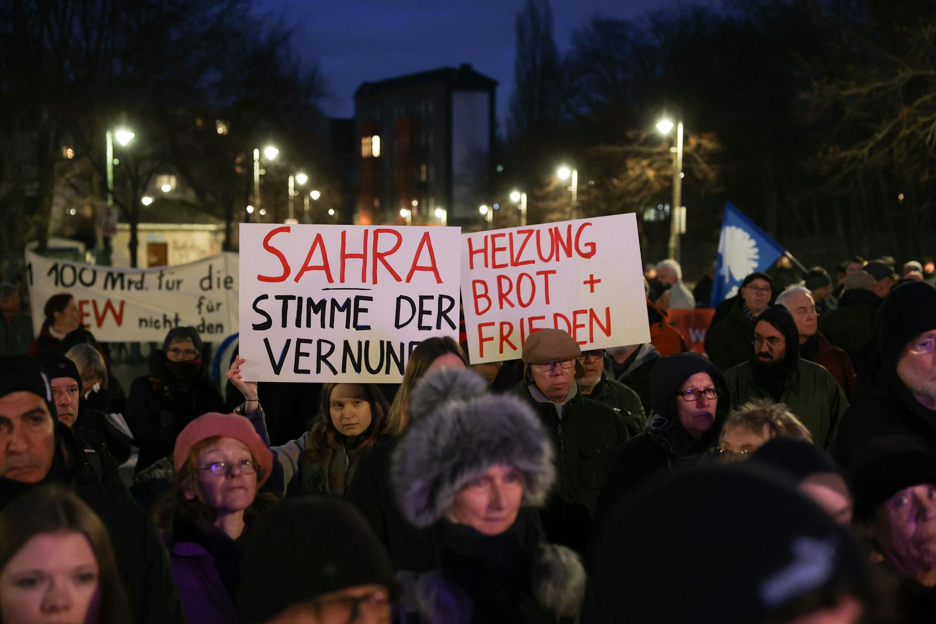 Besucher der Veranstaltung haben Plakate und Transparente mitgebracht. Darauf steht beispielsweise: „Sahra – Stimme der Vernunft“ und „Heizung, Brot + Frieden“.