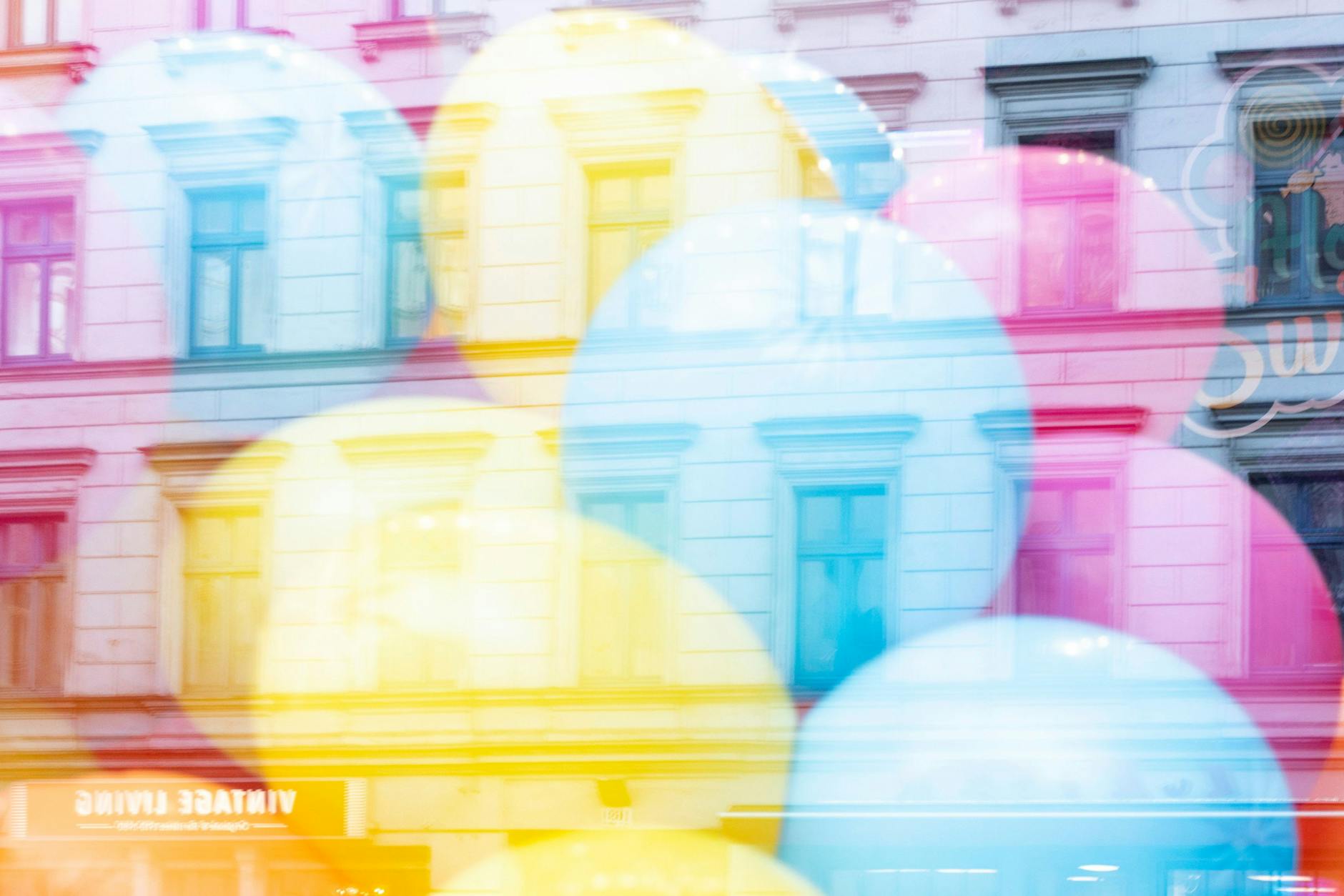 Die Oranienstraße 169 spiegelt sich in einem Ladenfenster mit Luftballons.