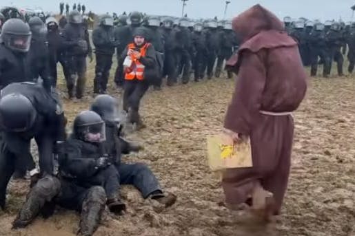 Lützerath: Ein als Mönch verkleideter Klimaaktivist schubste einen Polizisten, der knöcheltief im Schlamm feststeckt.