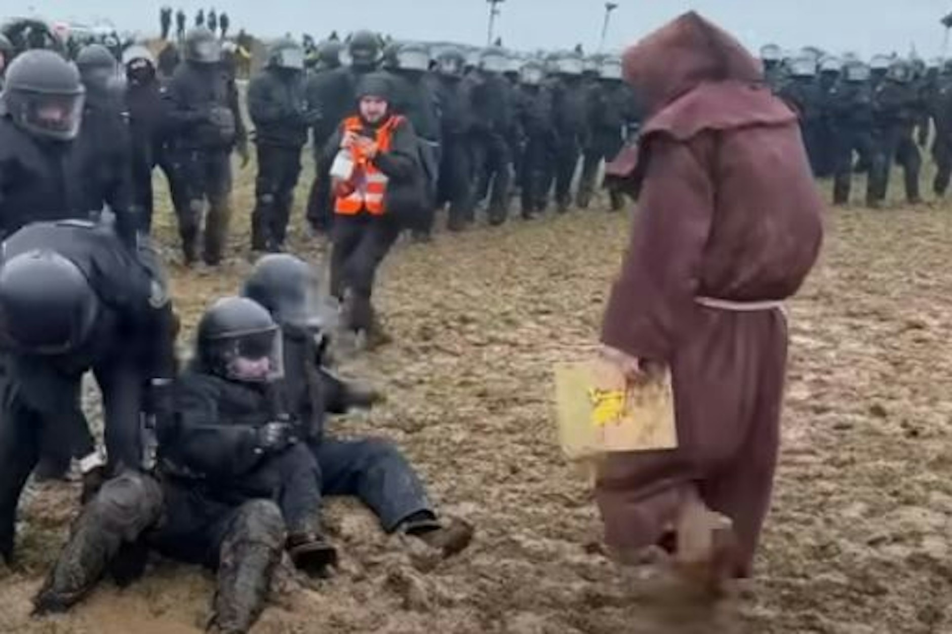 Lützerath: Ein als Mönch verkleideter Klimaaktivist schubste einen Polizisten, der knöcheltief im Schlamm feststeckt.