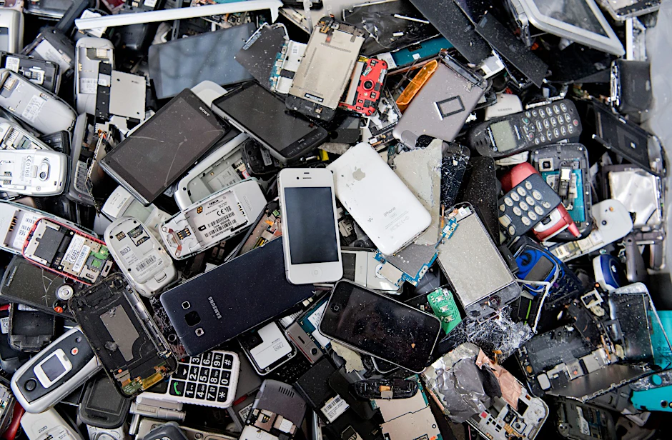 ARCHIV - Alte Handys und Smartphones liegen in einem Container, ehe sie geschreddert werden.  