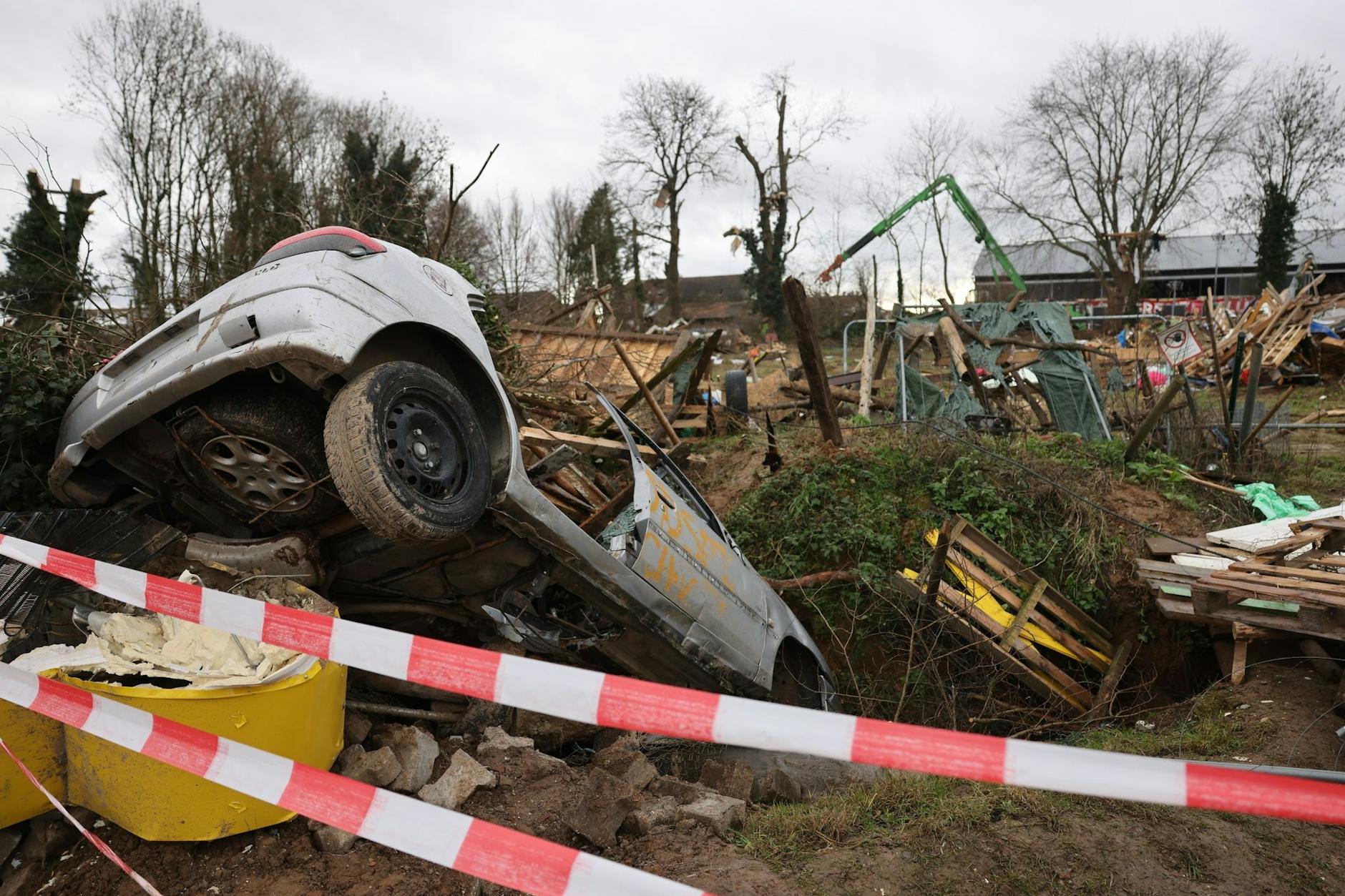 Trümmer der Holzhütten und ein Schrottauto liegen nach der Räumung in Lützerath herum.  