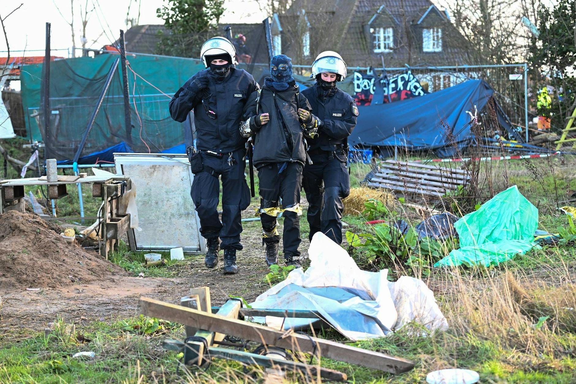 dpatopbilder - Polizisten führen einen Klimaaktivisten in Lützerath vom Gelände.