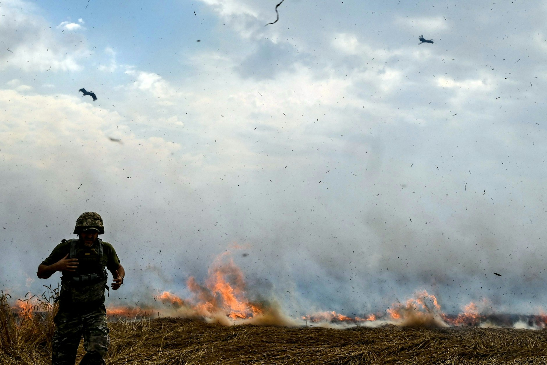 Ein Mann in Militäruniform im Juli 2022 in einem brennenden Weizenfeld in der Region Saporischschja, während russische Truppen Felder beschießen.